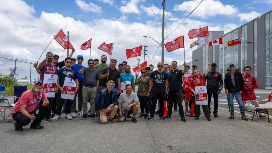 A large group of people holding up red unifor flags and "on strike" placecards