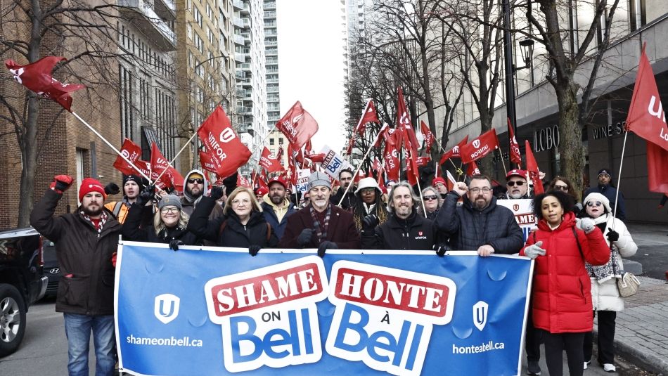 A large rally of people standing behind a banner waving flags