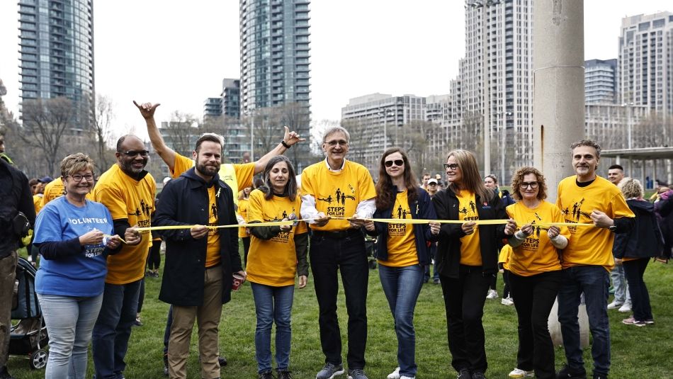 Steps for Life - Day of Mourning People stand in a line to cut a ceremonial yellow ribbon