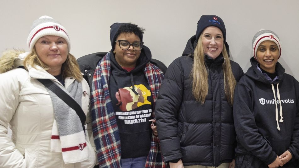 Four women wearing winter cloths and Unifor touqes smiling.