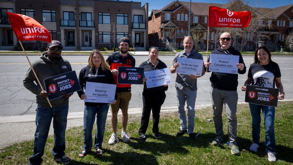 Seven people holding placards and Unifor flags