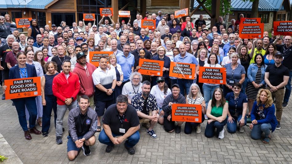 A group of people holding orange Safe Rates placards.