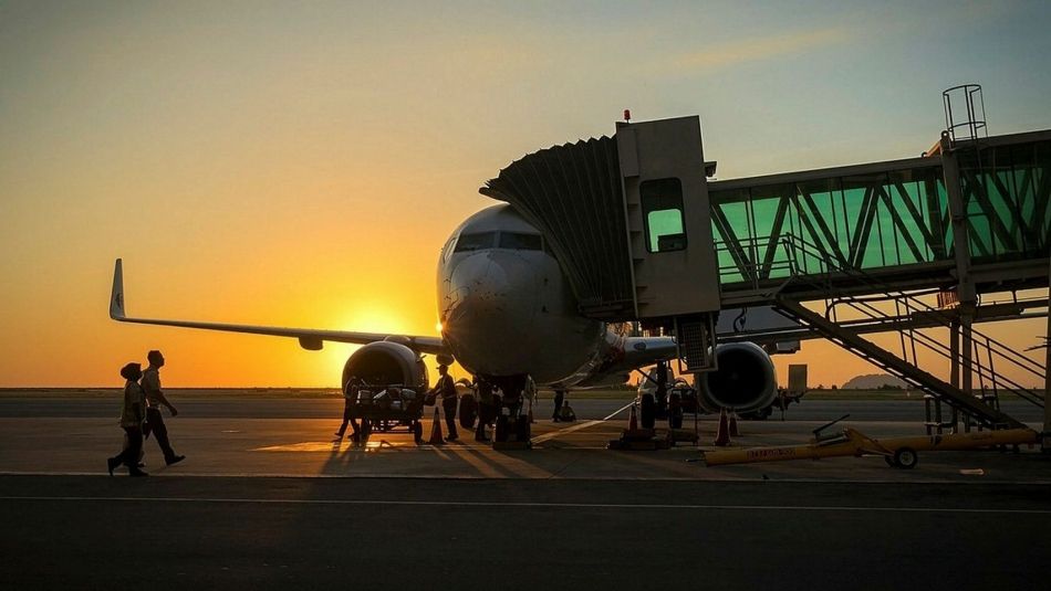 aircraft parked at gate with ground crew loading luggage