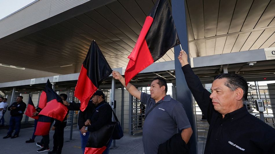 Three men holding up back and red flags