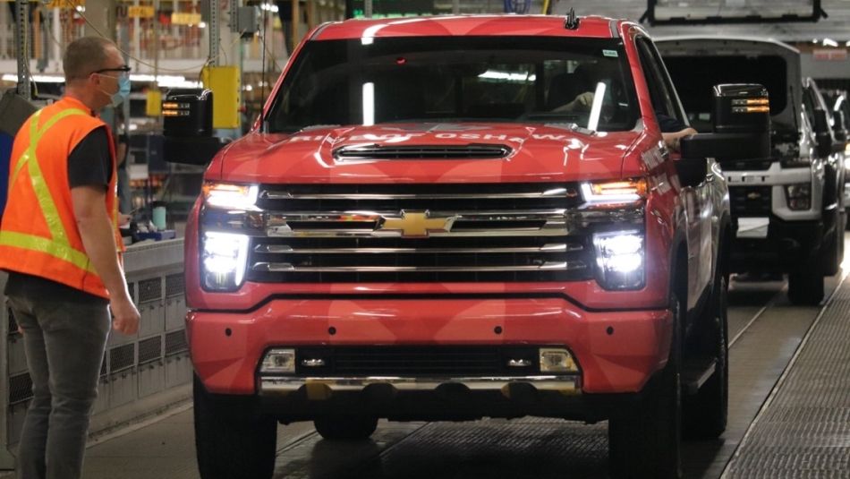 A Unifor member at GM Oshawa watches red truck roll off assembly line.