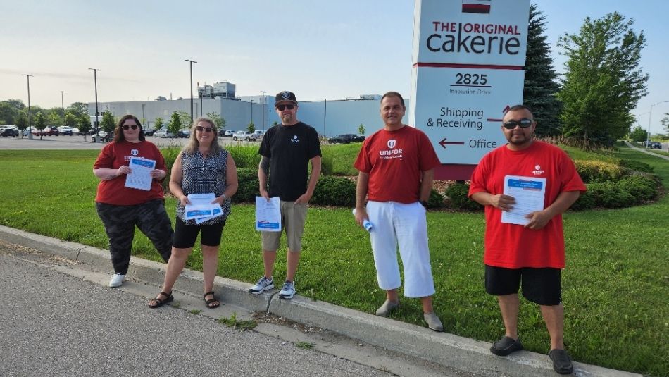 Five people stand in front of sign for The Original Cakerie 