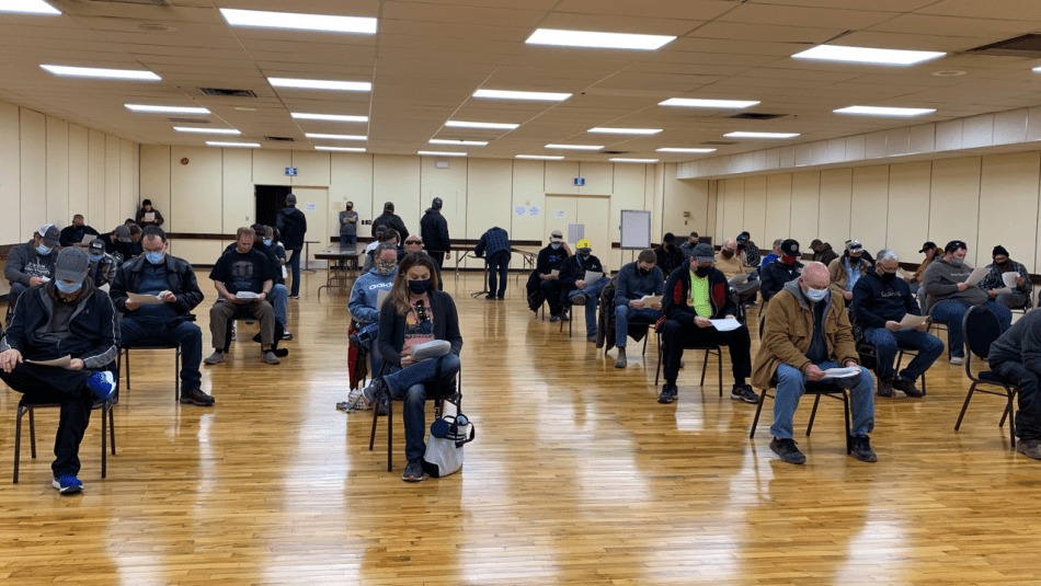 70 membres de la section locale 914 d'Unifor assis à six pieds l'un de l'autre dans un gymnase lors de l’assemblée de ratification.
