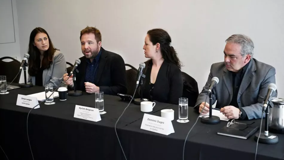 Four people sitting at mics behind a table