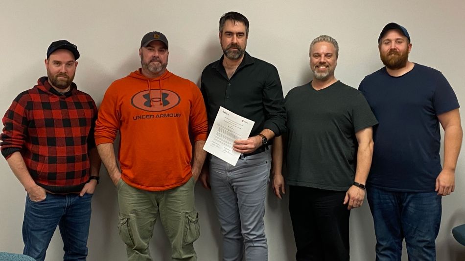 Five men standing in front of a cream wall.