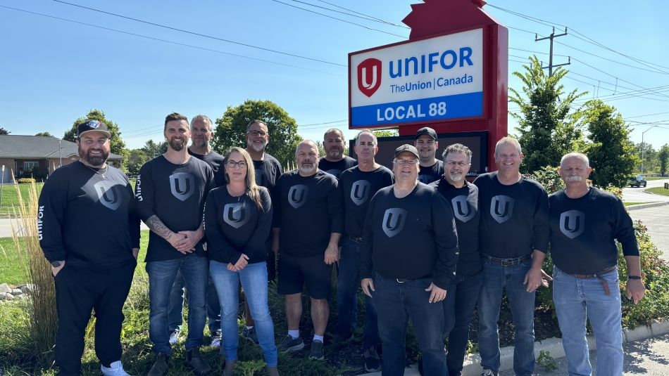 Un groupe de personnes se tenant à l'extérieur devant une pancarte de la section locale 88 d'Unifor