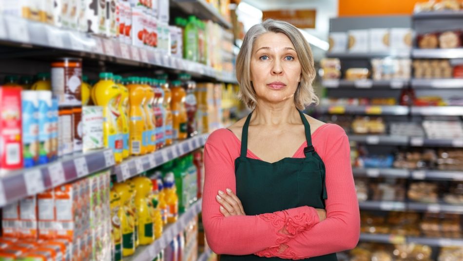 A women stands in a grocery isle with her arms folded.