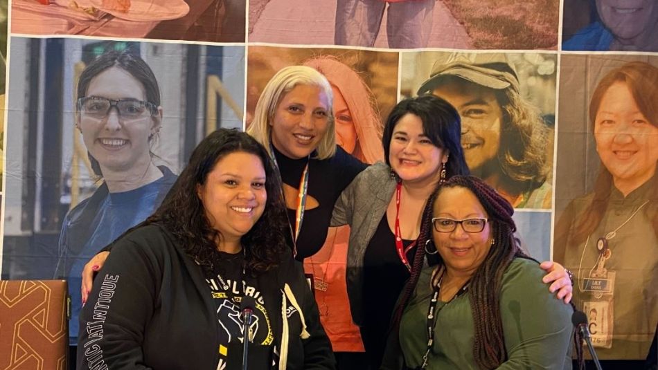 A group of four women of colour smile together. 