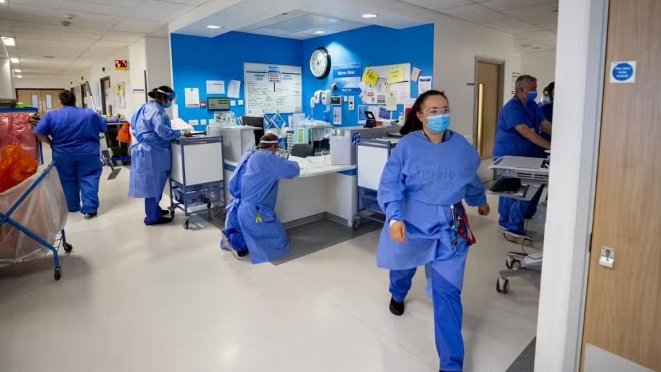 A busy hospital with five nurses running around doing their jobs.