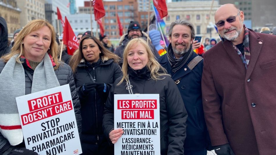 National officers of Unifor pose at a rally on Parliament Hill holding signs opposing health care privatization