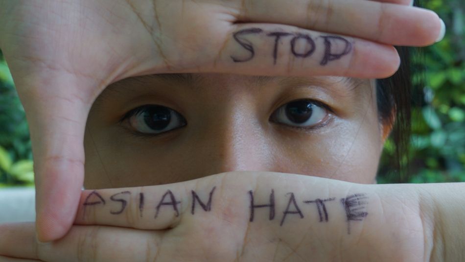 Asian woman holding up hands to show "Stop Asian Hate"