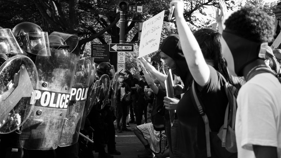 Black protesters butt up against police officers.