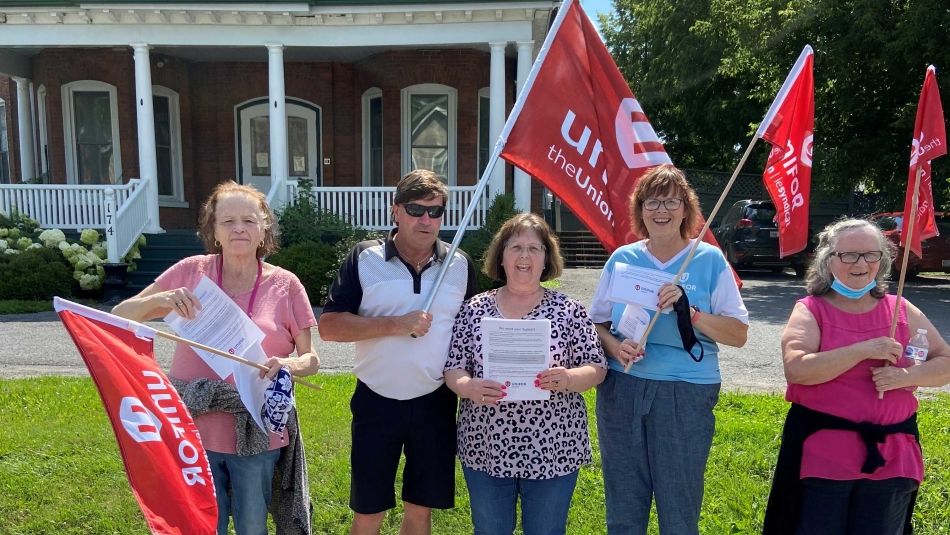 Workers hold Unifor flags during an information picket