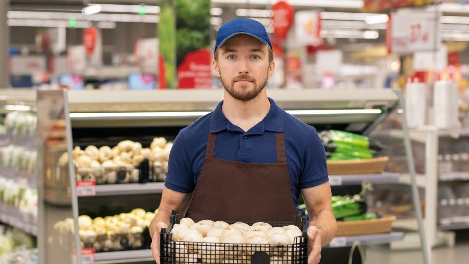 Man in uniform holding a box of mushrooms