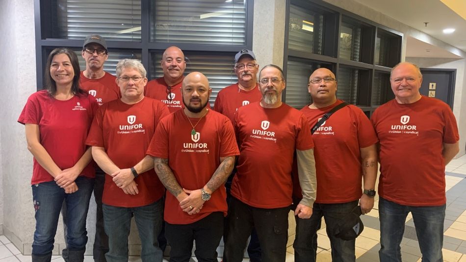 A group of people wearing red Unifor shirts pose together.