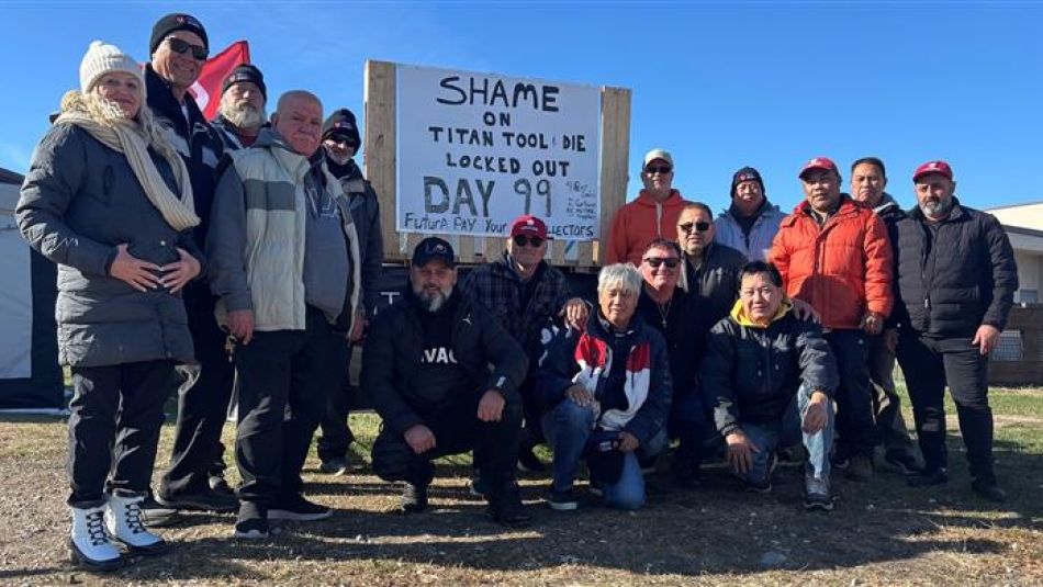 A large group stand outside around a sign that reads, "Shame on Titan Tool & Die locked out 99 days"