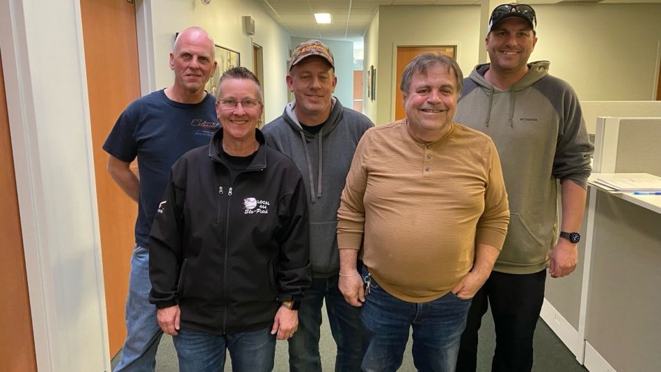 Five people posing for a picture in a hallway