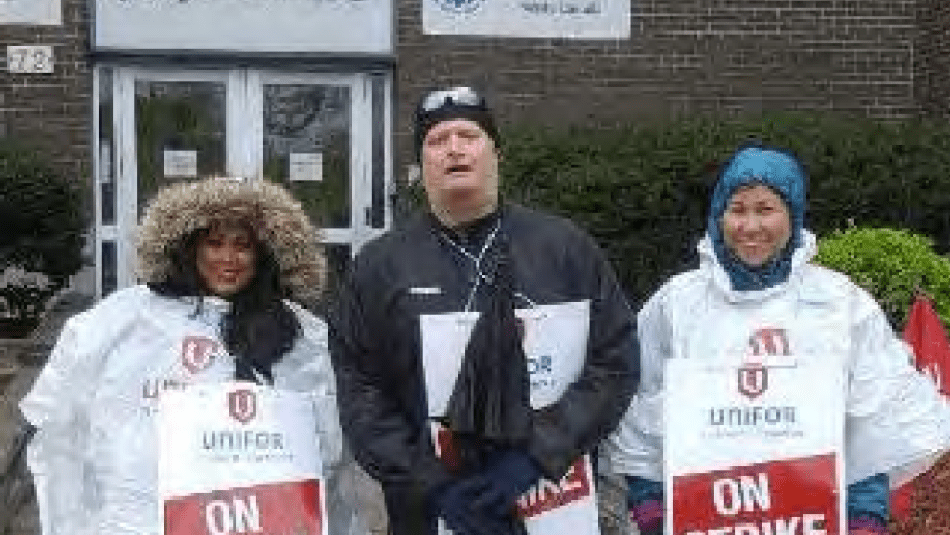 two women standing on either side of a man holding on strike signs