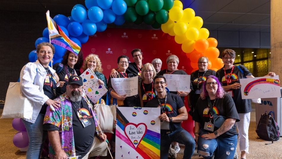 A group of people under a rainbow balloon display.