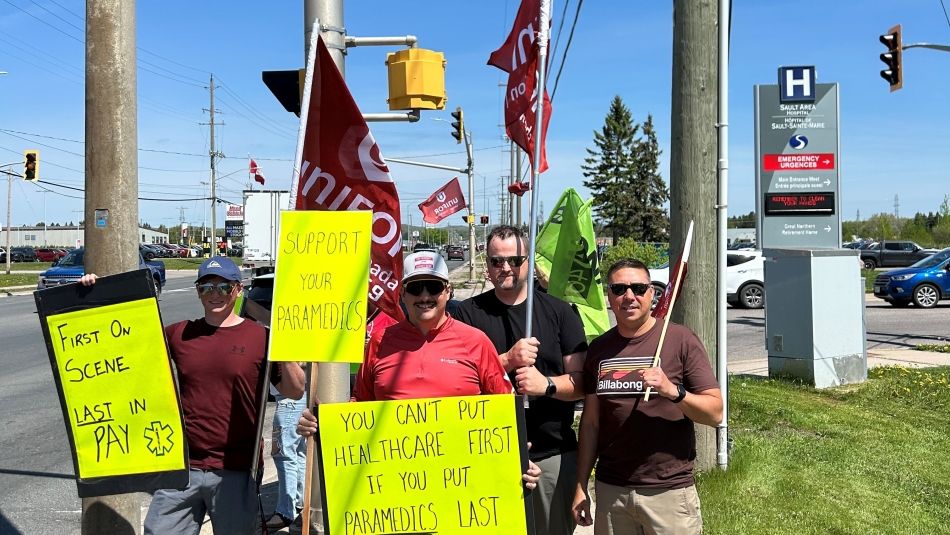 A goup of men standing on a sidewalk holding up bright yellow placecards
