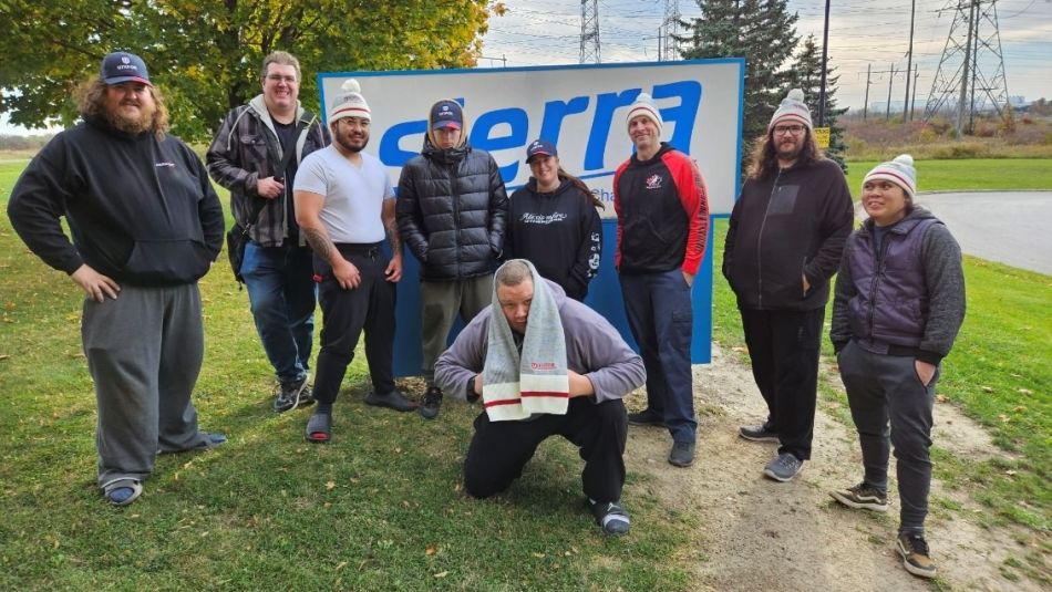 A group of nine people standing in front of an Sierra sign