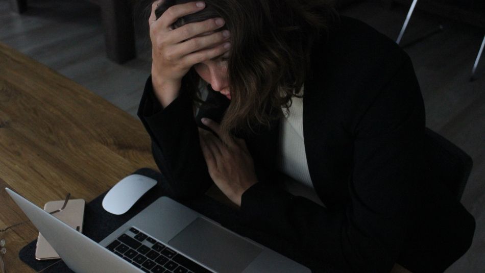 A stressed person sitting at a laptop.