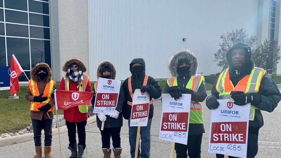 Kuehne + Nagel workers striking holding on strike signs and wearing warm winter gear.