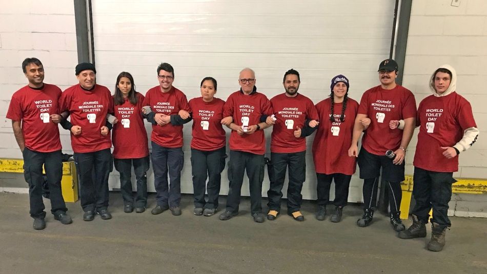 Ten people standing and linking arms. All wearing red shirts saying “World Toilet Day”.