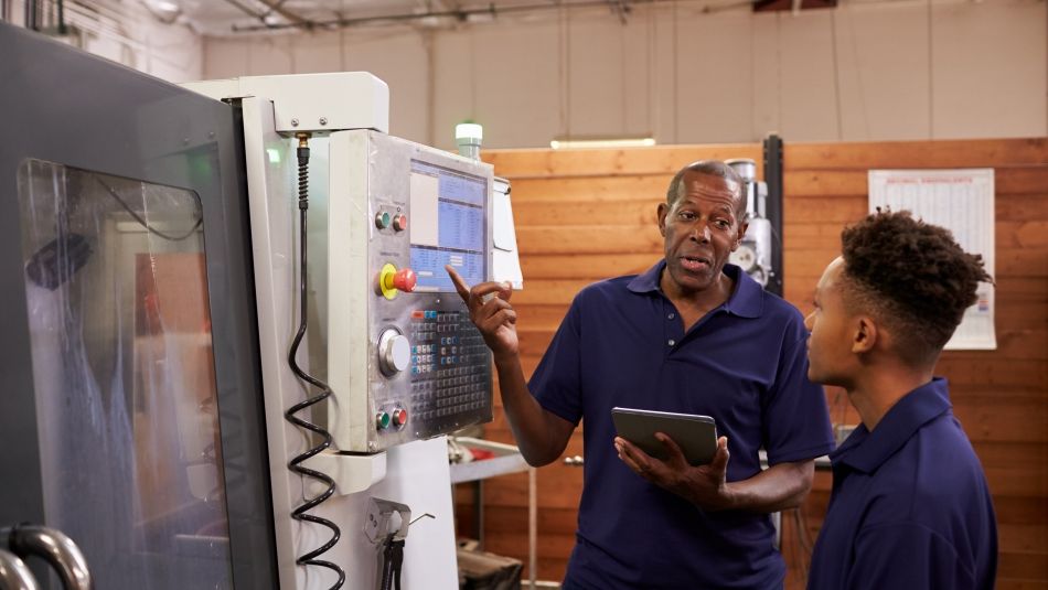 Engineer Training Young Male Apprentice On CNC Machine