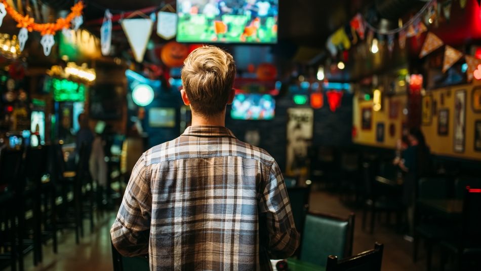 Person watching sports on a TV in a bar