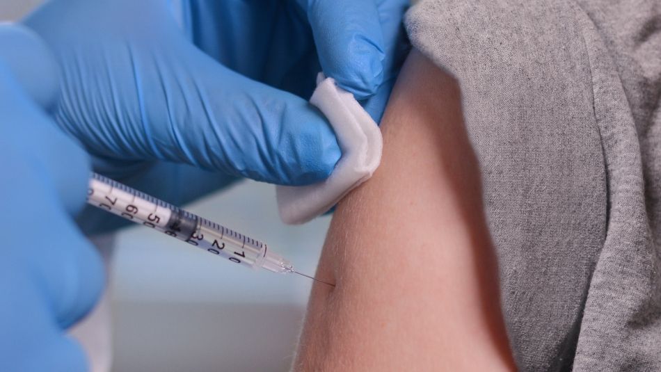 image close up of a needle jabbing an arm, someone getting a vaccine