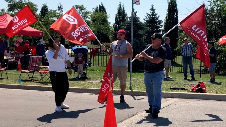 Unifor members from De Havilland wave flags on a picket line in Downsview.
