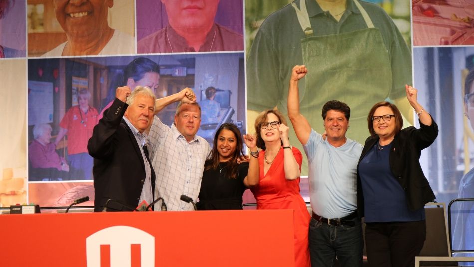 Unifor's leadership team raise their fists in solirdarity on the main stage of Canadian Council.