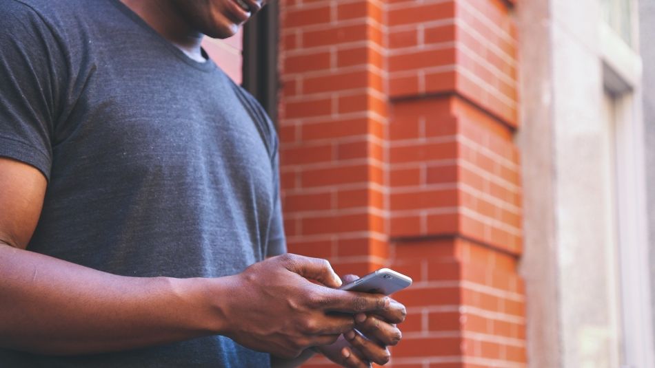 A man holds his cell phone while typing.