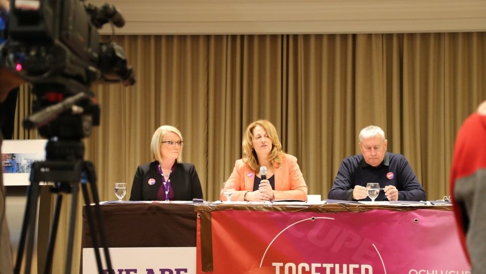 Katha Fortier, seated between two fellow union activists, speaks to health care workers.