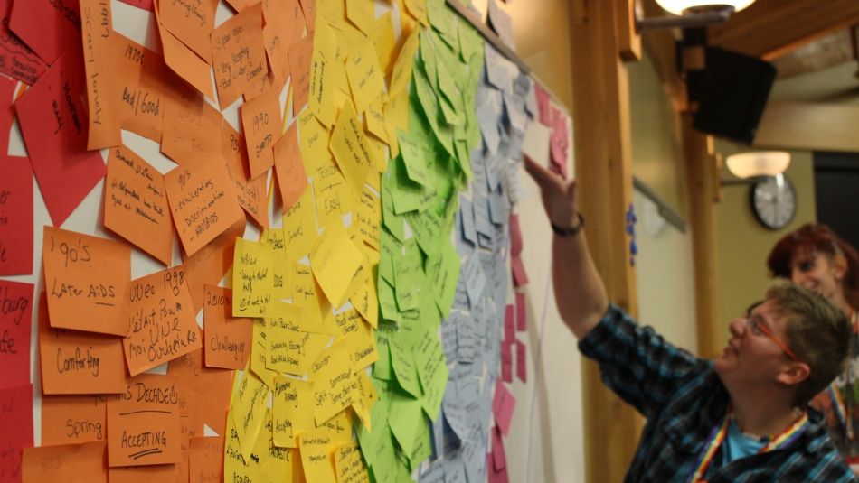 A Unifor member reads messages written on a rainbow of brightly coloured post-its.