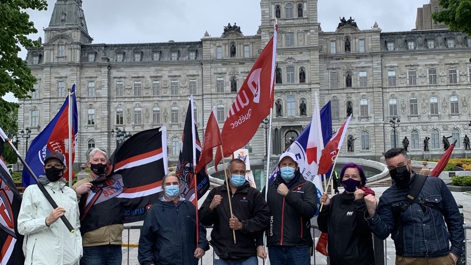 Member gather at the National Assembly in Quebec City for a vigil holding Unifor flags.