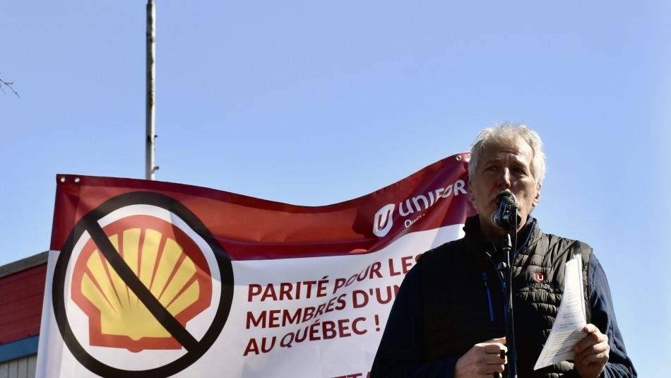 Unifor Quebec Director Renaud Gagné standing in front of a Unifor flag boycott of Shell products in Montreal