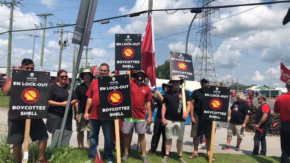 Members of Unifor Local 121 hold signs reading "Locked-out. Boycott Shell" on a picket line in Quebec. 