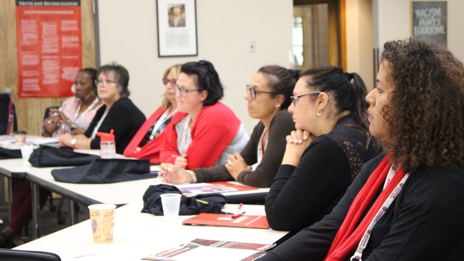 Seven Unifor sisters seated at a table during a Women's conference.