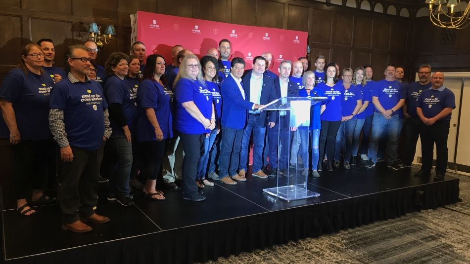 Jerry Dias poses at a podium with a large groupe of Unifor members.