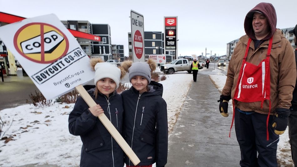 Les enfants d'un membre d'Unifor tiennent une pancarte à un piquet d'information pour les membres de la section locale 594 d'Unifor en lock-out.