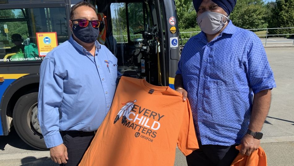 B.C. transit operators distribute orange t-shirts in front of a bus in Vancouver