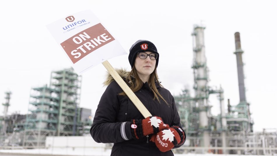 A unifor member holds a strike sign.