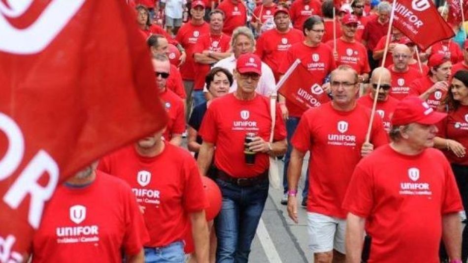 Bell members marching at a rally dressed in red Unifor shirts holding flags