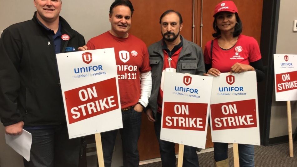 Unifor members hold strike signs.